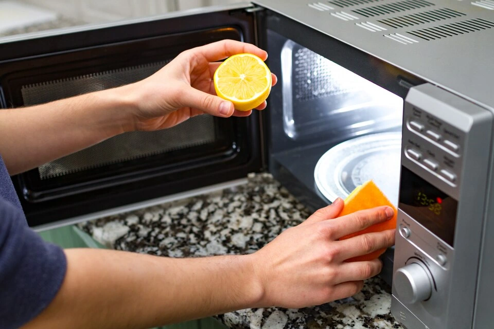 a woman scrubbing stain in microwave with lemon